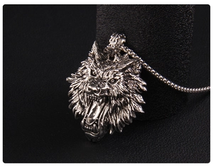 Detailed close-up of a silver wolf head pendant with textured fur and metal ball chain