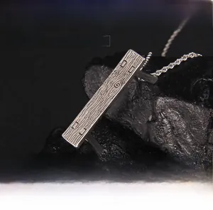 Detailed macro view of rectangle necklace pendant with wood grain texture and cable chain