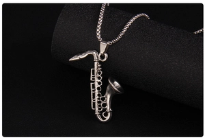 Close-up detail of silver stainless steel saxophone pendant with intricate engraved keys