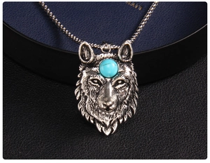 Macro close-up of a wolf head pendant with a blue gemstone inlay on a stainless steel chain