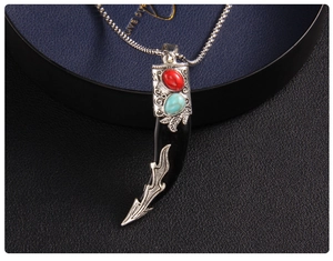 Macro shot of tribal tooth pendant featuring red and turquoise stones with wheat chain