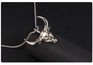Gros plan d'un pendentif tête de taureau argenté vintage avec gravure sur chaîne box