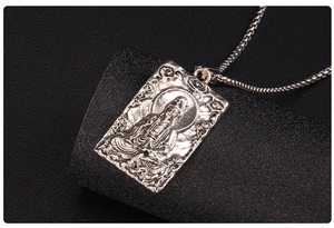 Dettaglio del rilievo del Buddha Guanyin su un ciondolo rettangolare in acciaio inox