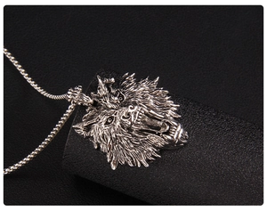 Macro shot of silver wolf head pendant with detailed textures on a black textured base