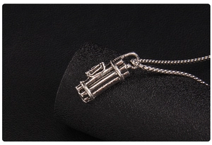 Macro shot of silver golf bag pendant necklace with detailed texture on black background