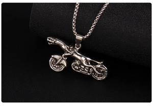 Macro view of vintage silver leopard motorcycle pendant on black textured surface