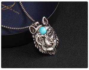 Detail shot of vintage silver wolf head pendant with blue stone on black leather background