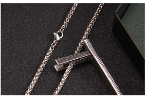 Macro detail of silver stainless steel necklace with textured wood grain T-bar pendant
