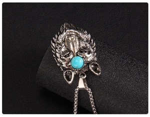 Detailed macro shot of an antique silver wolf head pendant with a blue stone inlay