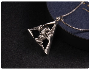 Macro shot of a gothic skull and skeleton hands in a silver triangle pendant