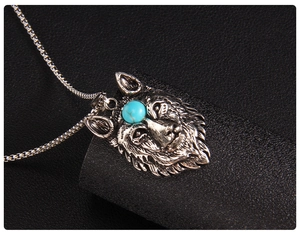 Macro shot of silver wolf head pendant with blue stone and vintage engraving detail