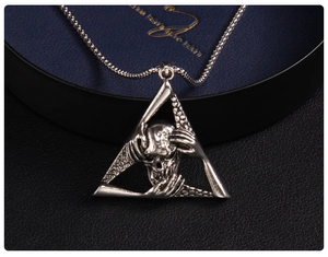 Macro shot of gothic skull and hands pendant on blue velvet within a triangle frame