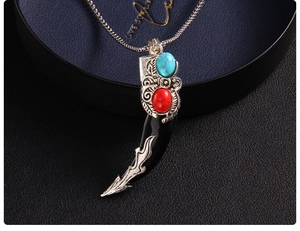 Detail of vintage wolf tooth pendant with silver leaf texture and turquoise inlay