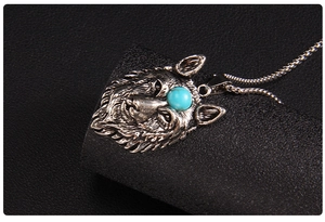 Macro detail of wolf head pendant with blue gemstone and vintage silver chain link