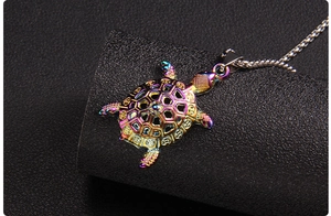 Macro detail of rainbow turtle pendant with geometric hollow shell on black leather