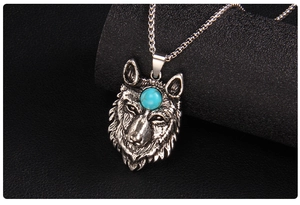 Macro shot of silver wolf head pendant with blue turquoise inlay on a black background