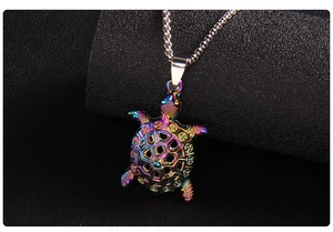 Macro shot of colorful turtle pendant with hollow geometric shell on a black leather base