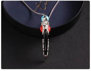 Macro detail of retro wolf tooth pendant with silver metalwork and colorful beads