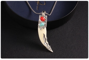 Macro detail of retro wolf tooth pendant with red gemstone and turquoise inlay on box