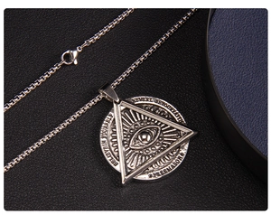 Makroaufnahme von silbernem Evil Eye Anhänger mit gravierter Freimaurer-Münze auf Leder