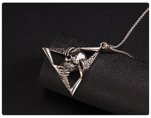 Macro detail of gothic skull necklace with triangle frame and oxidized metal finish