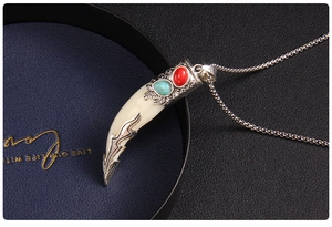 Detailed macro view of vintage ethnic wolf tooth pendant with red and blue gemstones