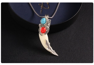 Close-up of vintage wolf tooth pendant with turquoise red stones and silver carvings