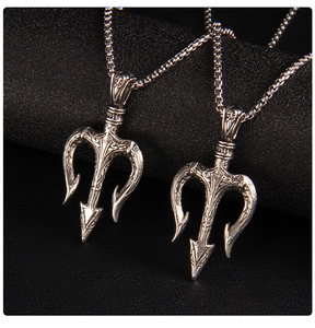 Macro view of silver trident pendants with intricate retro carvings on black background