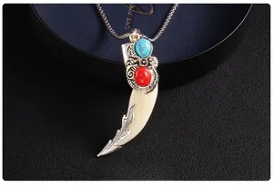 Detailed view of vintage wolf tooth pendant with turquoise stones and engraved silver finish