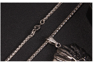 Detailed close-up of eagle feather pendant with wheat chain on black leather