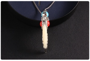 Close-up of ethnic wolf tooth pendant with silver base and red blue beads on ball chain
