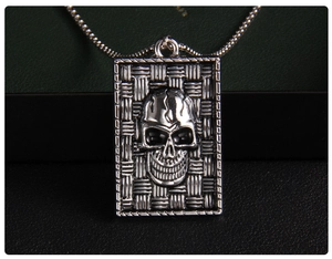 Detailed close-up of a 3D skull pendant with woven texture and box chain in silver metal