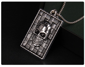 Macro shot of punk style square skull pendant with detailed woven texture on vintage silver metal