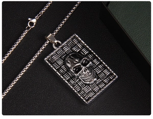 Macro shot of punk style rectangular skull pendant with woven texture on black leather
