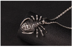 Macro side view of vintage spider pendant necklace with detailed shell texture on black