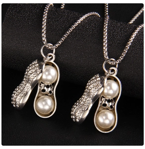 Vue détaillée du pendentif cacahuète avec cristaux blancs et perles sur fond sombre
