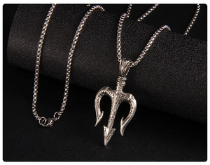Detailed close-up of retro silver trident pendant with box chain on black leather