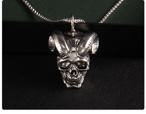 Macro shot of vintage silver skull pendant with detailed horns on long bead chain