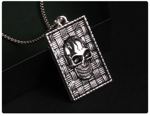 Macro shot of punk style square skull pendant with detailed woven texture on silver metal