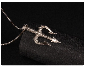 Macro detail of silver trident pendant with baroque relief patterns on black leather