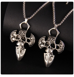 Macro detail of gothic skull cross pendants with vintage finish on black leather background