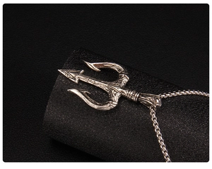 Macro shot of silver trident pendant with detailed European floral engravings and box chain