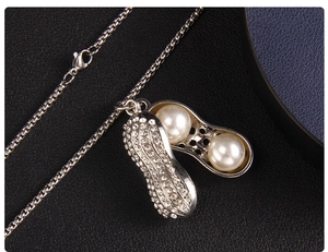 Gros plan du pendentif cacahuète argenté avec perles blanches et strass brillants