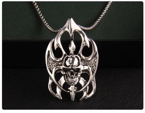 Détail d'un pendentif tête de mort punk argenté avec motifs de flammes et fini vintage