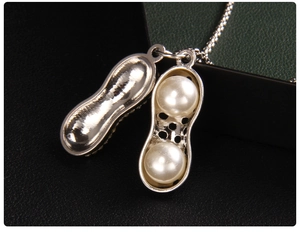 Gros plan d'un collier pendentif cacahuète argenté avec deux perles sur fond de cuir noir