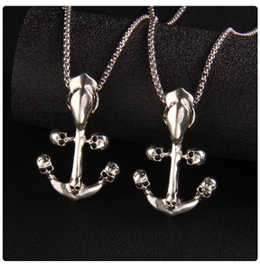 Macro shot of twin anchor necklaces with skull details on black leather background