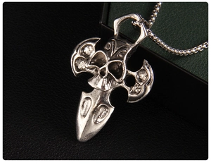 Macro shot of gothic silver skull pendant with cross and dagger on black leather texture