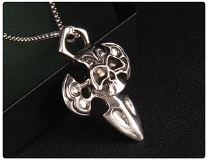 Detail of gothic silver skull cross axe pendant on box chain over black leather background