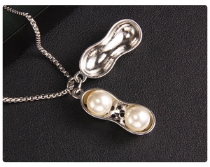 Macro d'un collier pendentif cacahuète ouvrant avec deux perles blanches à l'intérieur