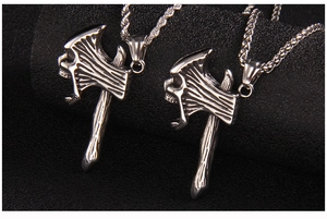 Détail de pendentifs hache en acier avec relief de crâne sur chaînes corde et blé